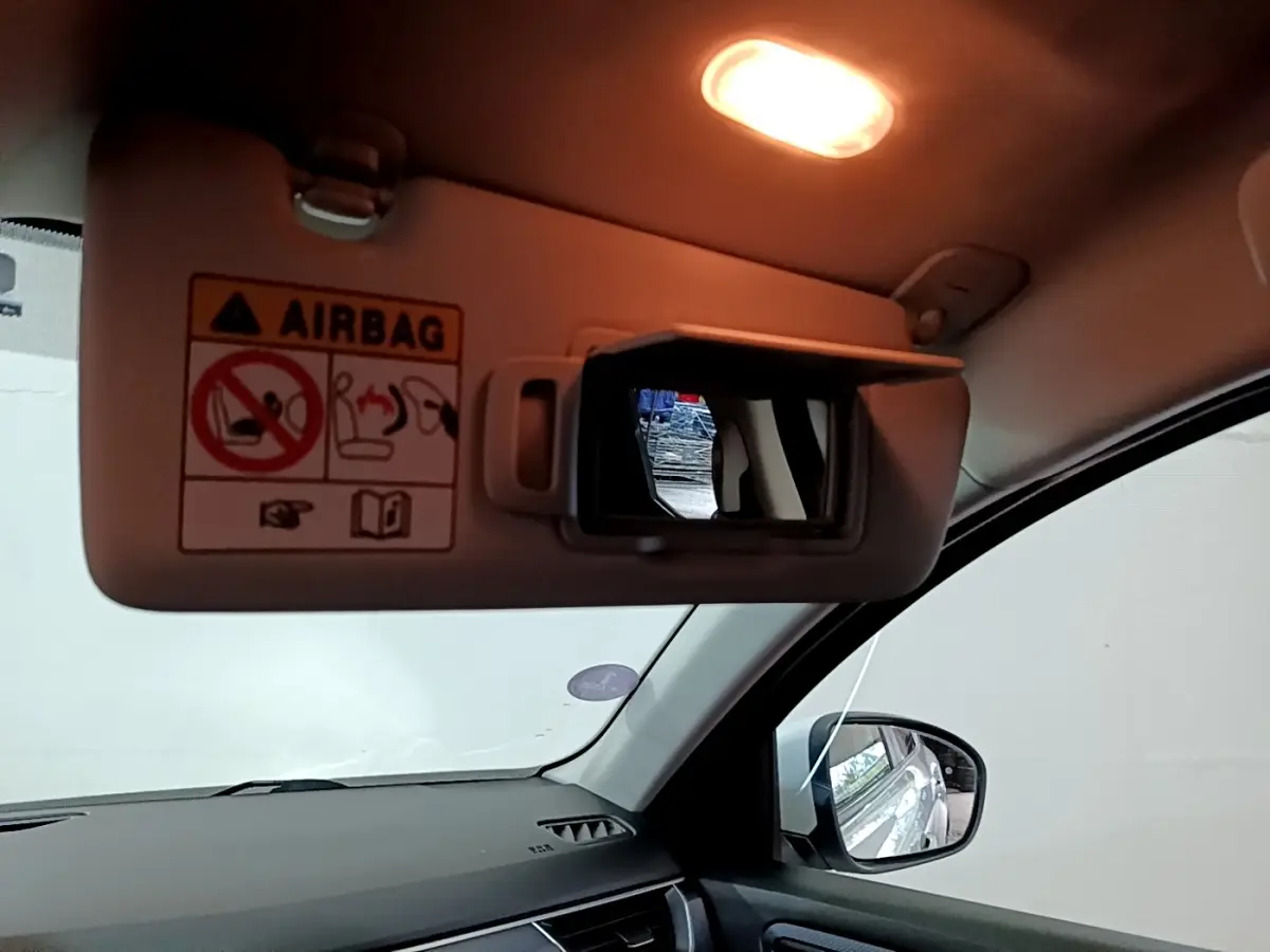 Intérieur du Renault Arkana blanc, vue côté passager avec pare-soleil et miroir éclairé ouvert.