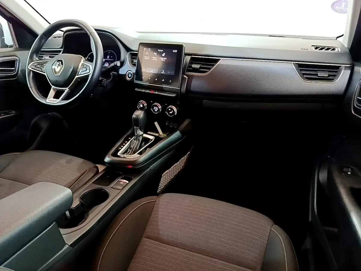 Intérieur de la Renault Arkana Evolution E-Tech 2023 vu côté passager, tableau de bord noir avec écran tactile central.