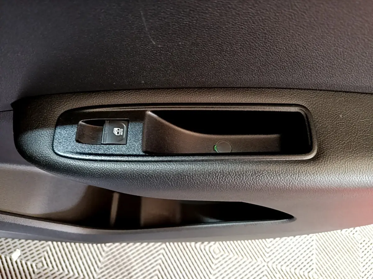 Gros plan sur la poignée intérieure noire et le bouton de verrouillage de porte côté conducteur du Renault Arkana blanc 2023.