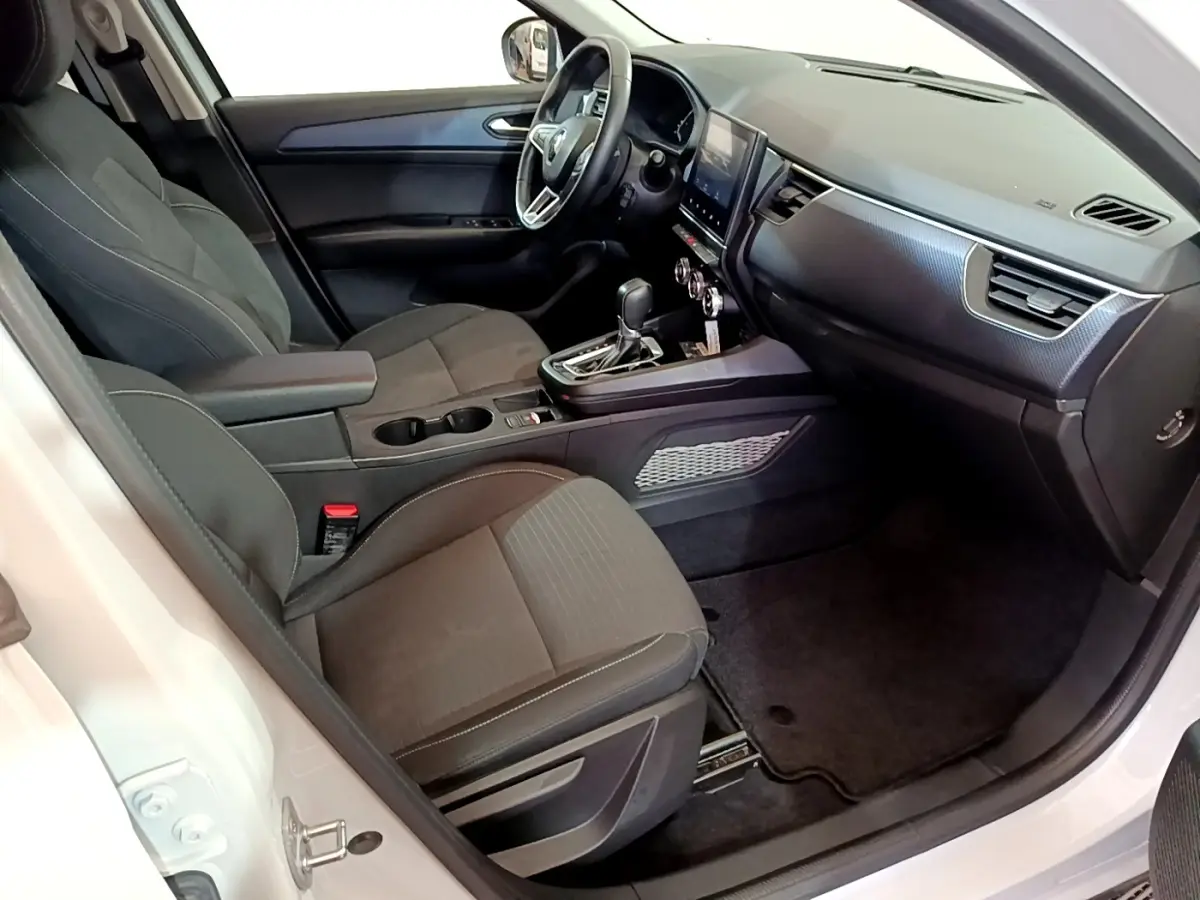 Vue intérieure côté conducteur du Renault Arkana blanc, mettant en valeur le tableau de bord et la console centrale moderne.