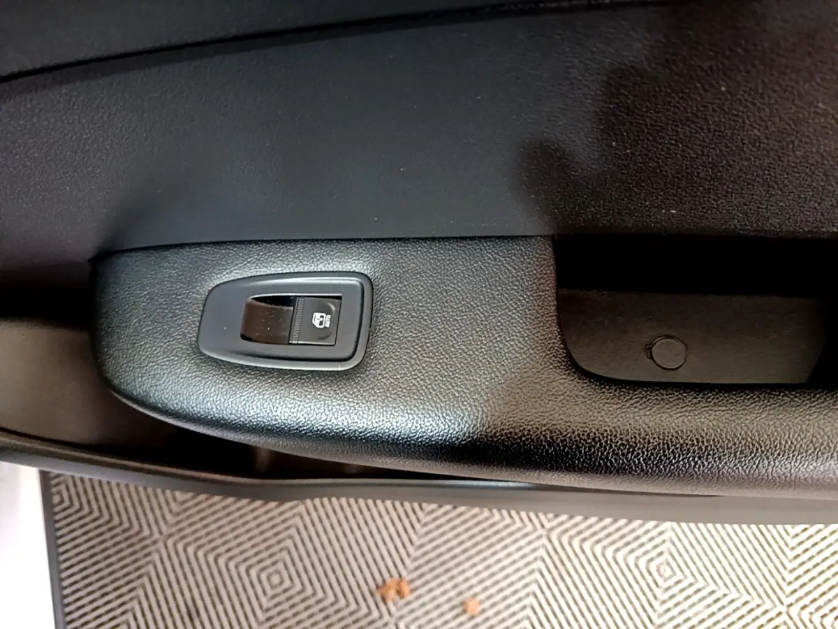 Détail de la commande de lève-vitre électrique sur la porte intérieure noire d’un Renault Arkana blanc 2023.