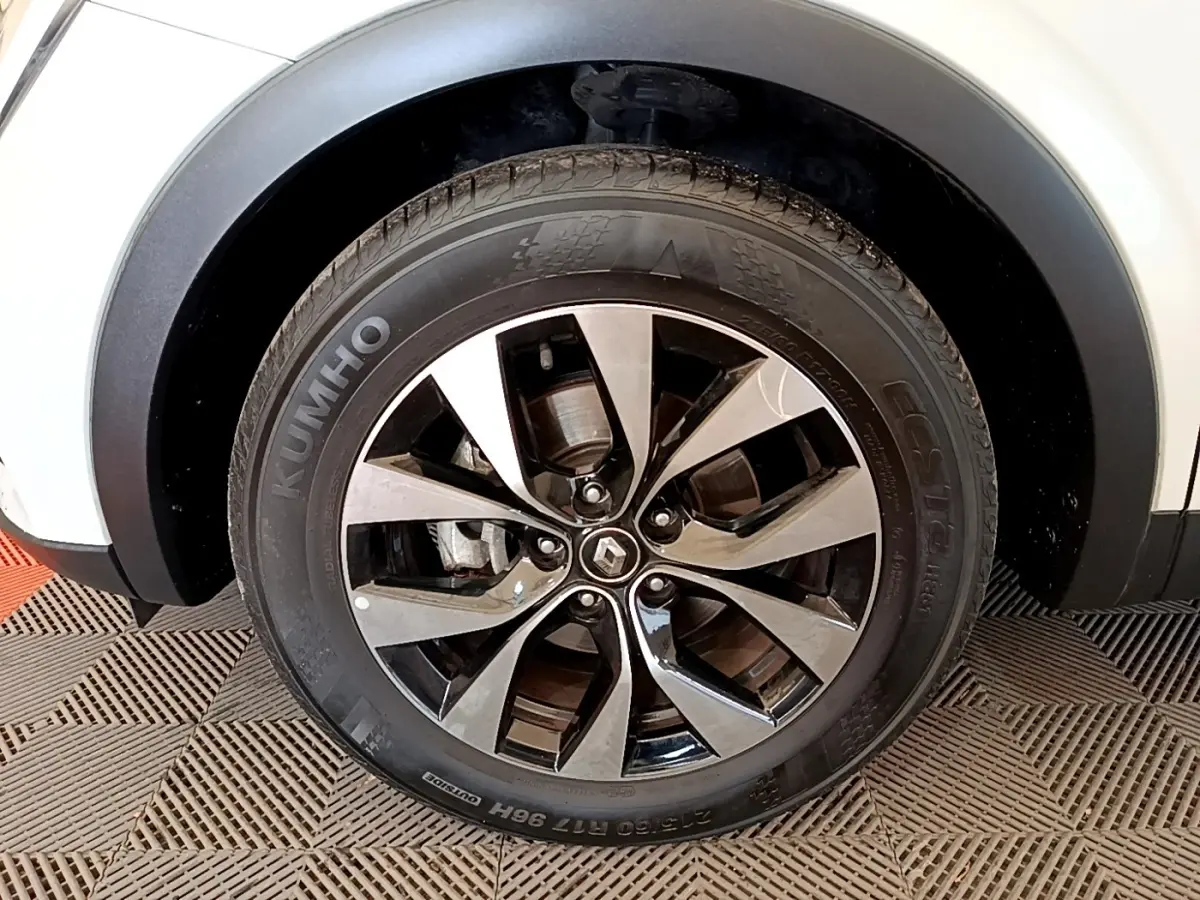 Gros plan sur la roue avant droite du Renault Arkana blanc, avec jante alliage bicolore et logo Renault central.