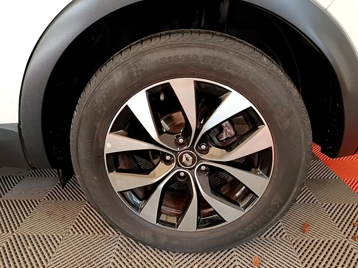 Gros plan sur la roue avant droite d’un Renault Arkana blanc, jante alliage bicolore au design moderne.