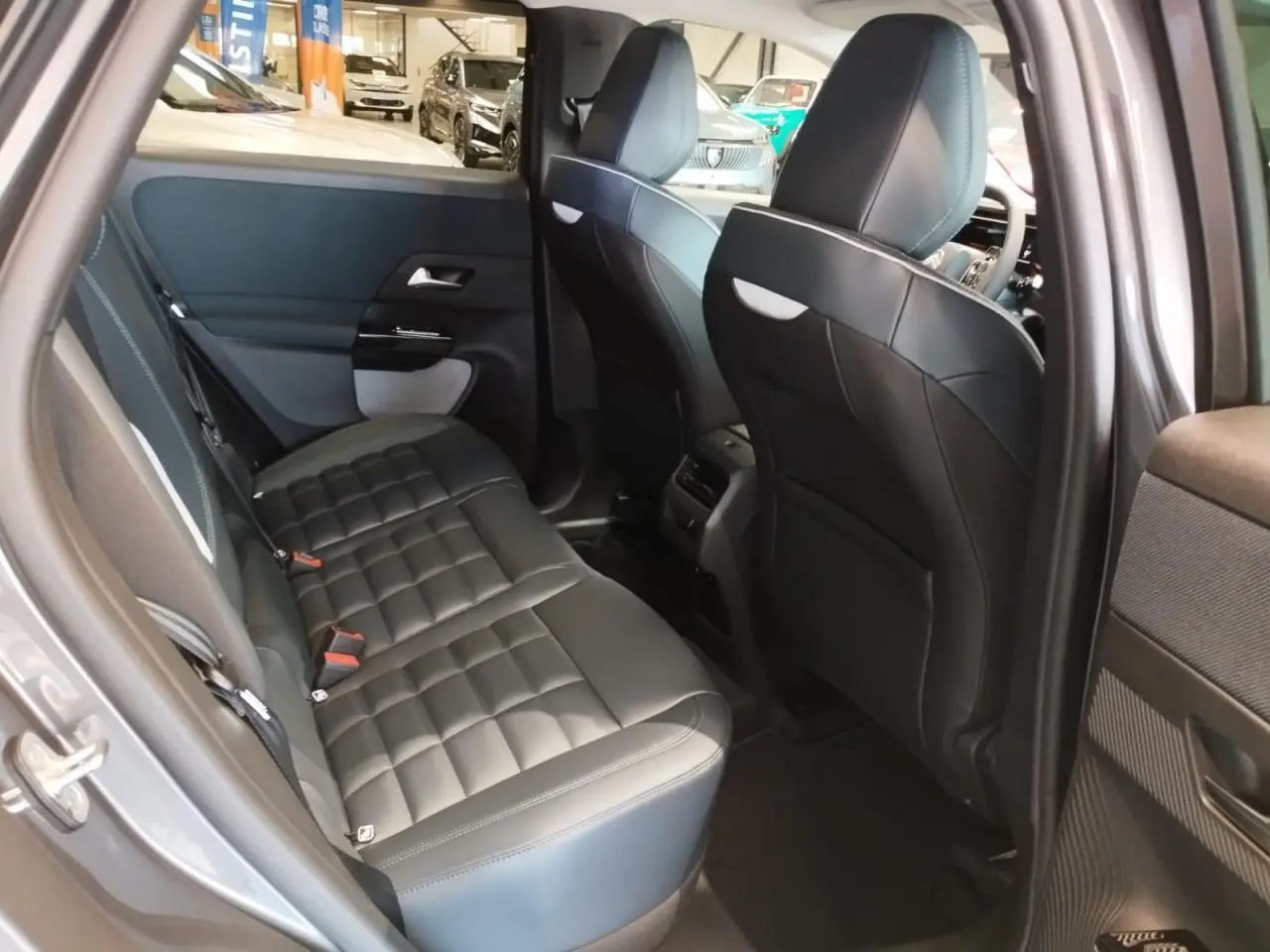 Vue intérieure côté gauche de la banquette arrière en cuir noir du Citroën C5 Aircross gris, avec sièges avant visibles.