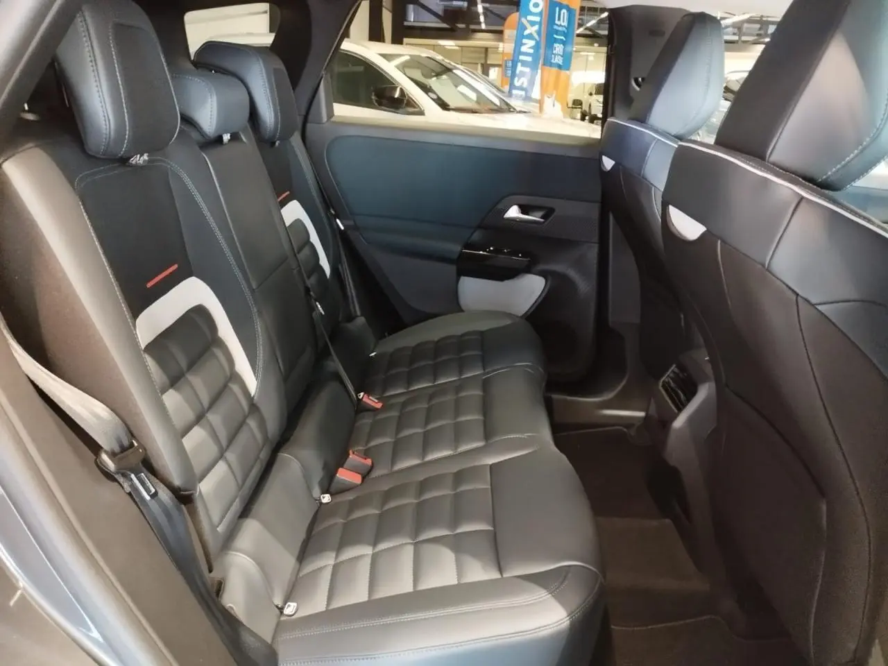 Vue latérale intérieure des sièges arrière en cuir noir avec surpiqûres blanches du Citroën C5 Aircross gris 2026.