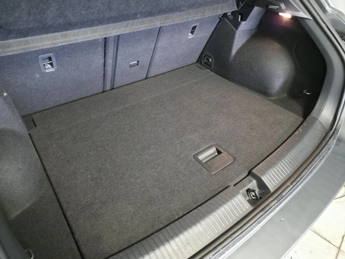 Coffre spacieux du Volkswagen T-Roc gris 2025 vu de dessus, avec plancher plat et éclairage intérieur.