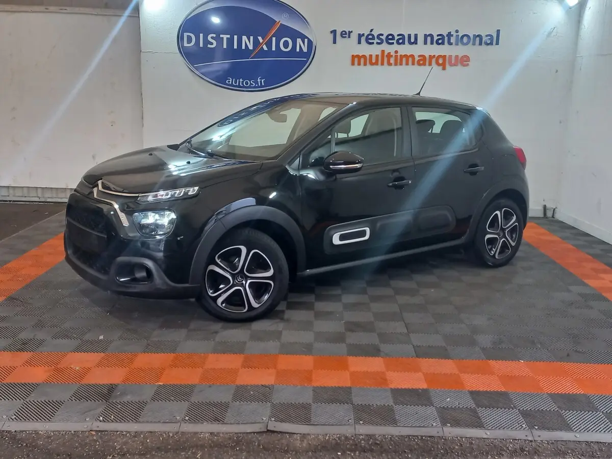 Citroën C3 noire vue de profil droit en intérieur, avec protections latérales blanches et jantes distinctives.