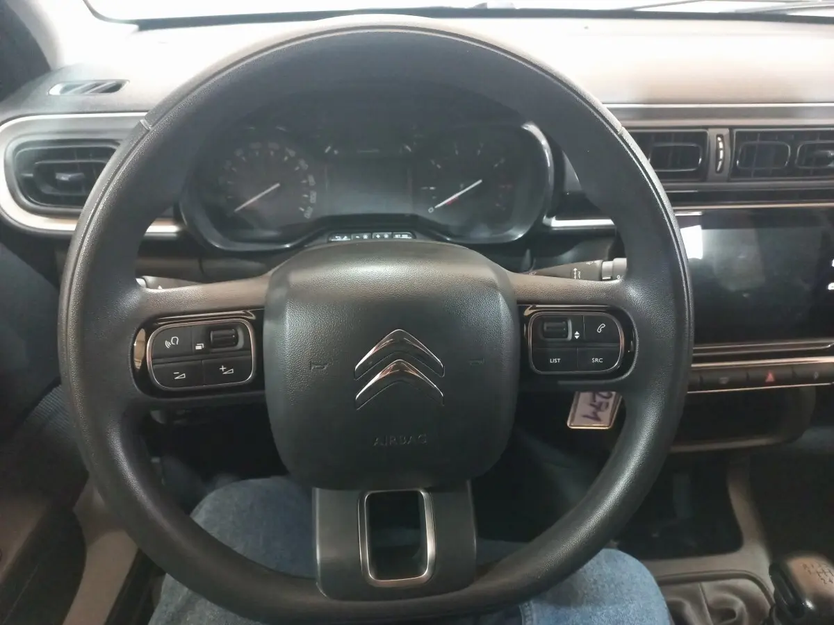Vue rapprochée du volant multifonctions noir de la Citroën C3 2024 avec tableau de bord et écran tactile.