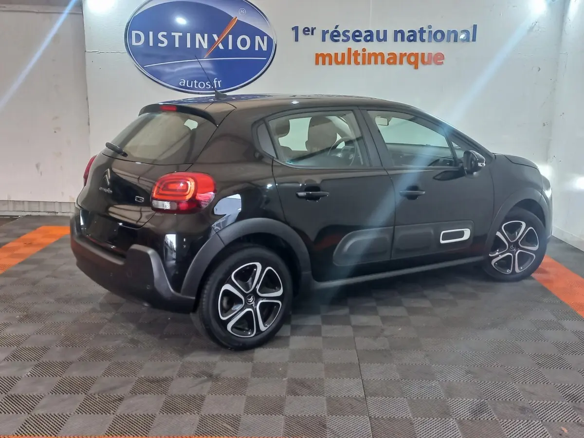 Vue 3/4 arrière droite d'une Citroën C3 noire 2024 avec protections latérales et jantes distinctives.
