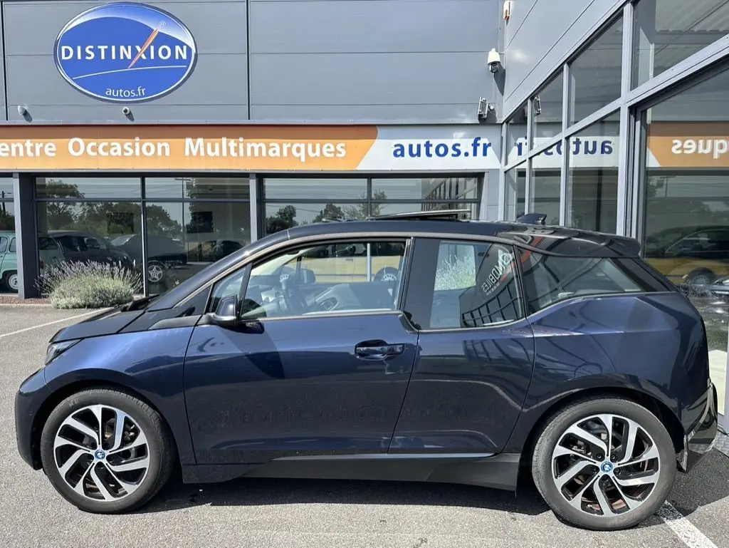 Profil côté gauche d'une BMW I3 électrique bleue édition Windmill Atelier 2022, avec jantes distinctives et toit noir.