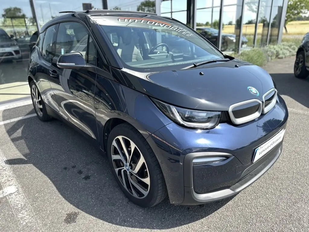 BMW i3 électrique bleue vue en 3/4 avant droit, avec capot noir et jantes distinctives bicolores.