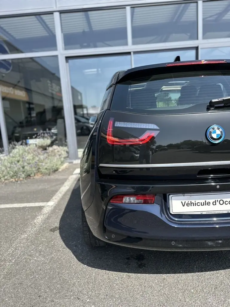 Vue arrière d'une BMW i3 électrique bleue 2022, mettant en valeur ses feux arrière LED distinctifs et son design compact.