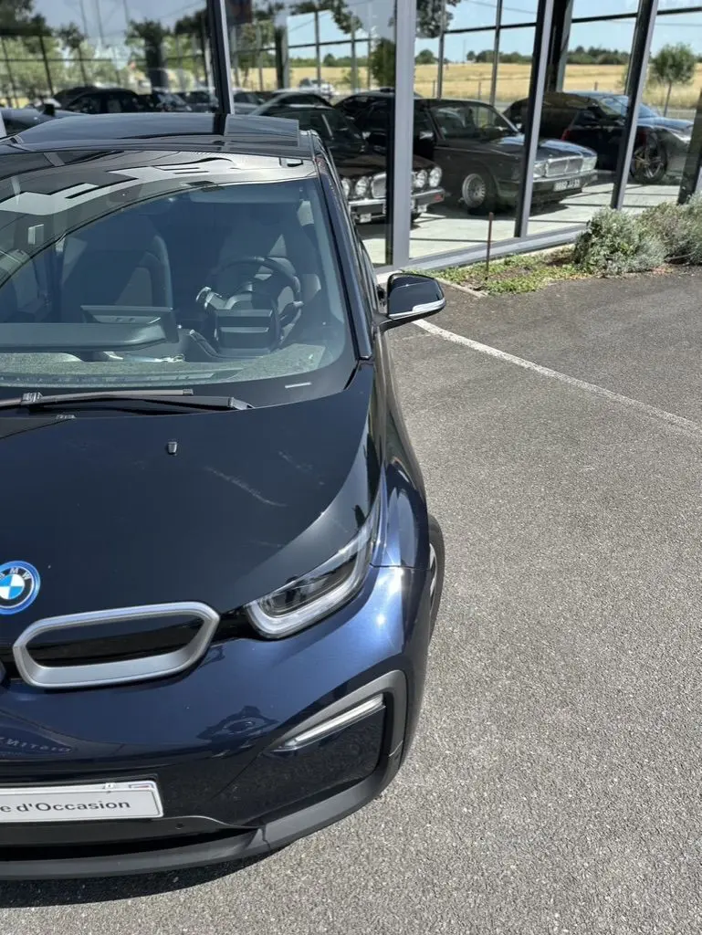 Vue 3/4 avant droite d'une BMW i3 bleue électrique 2022, avec ses phares LED et calandre caractéristique visibles.