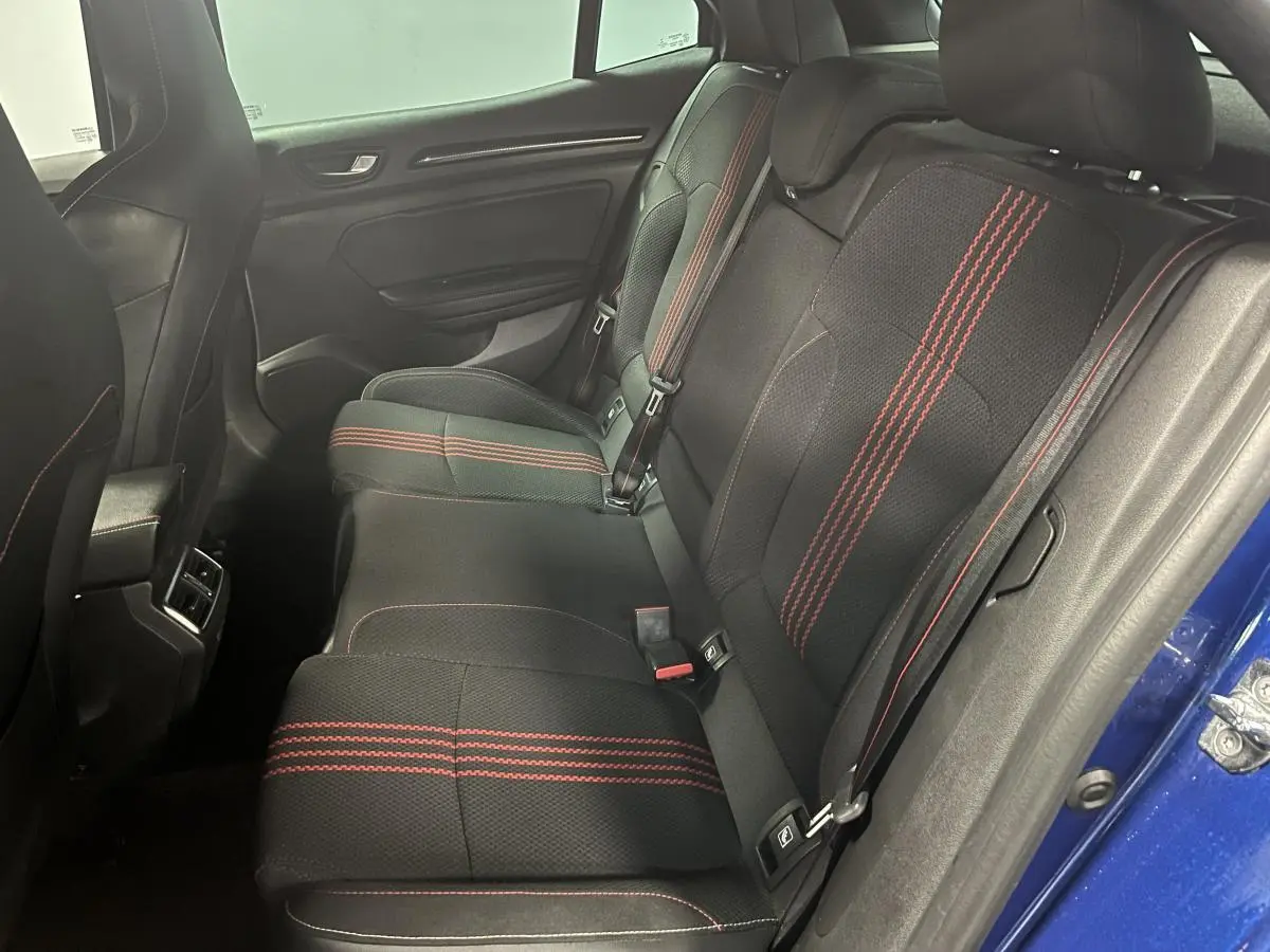 Vue latérale droite de l'intérieur arrière de la Renault Mégane bleu, sièges noirs avec surpiqûres rouges sportives.