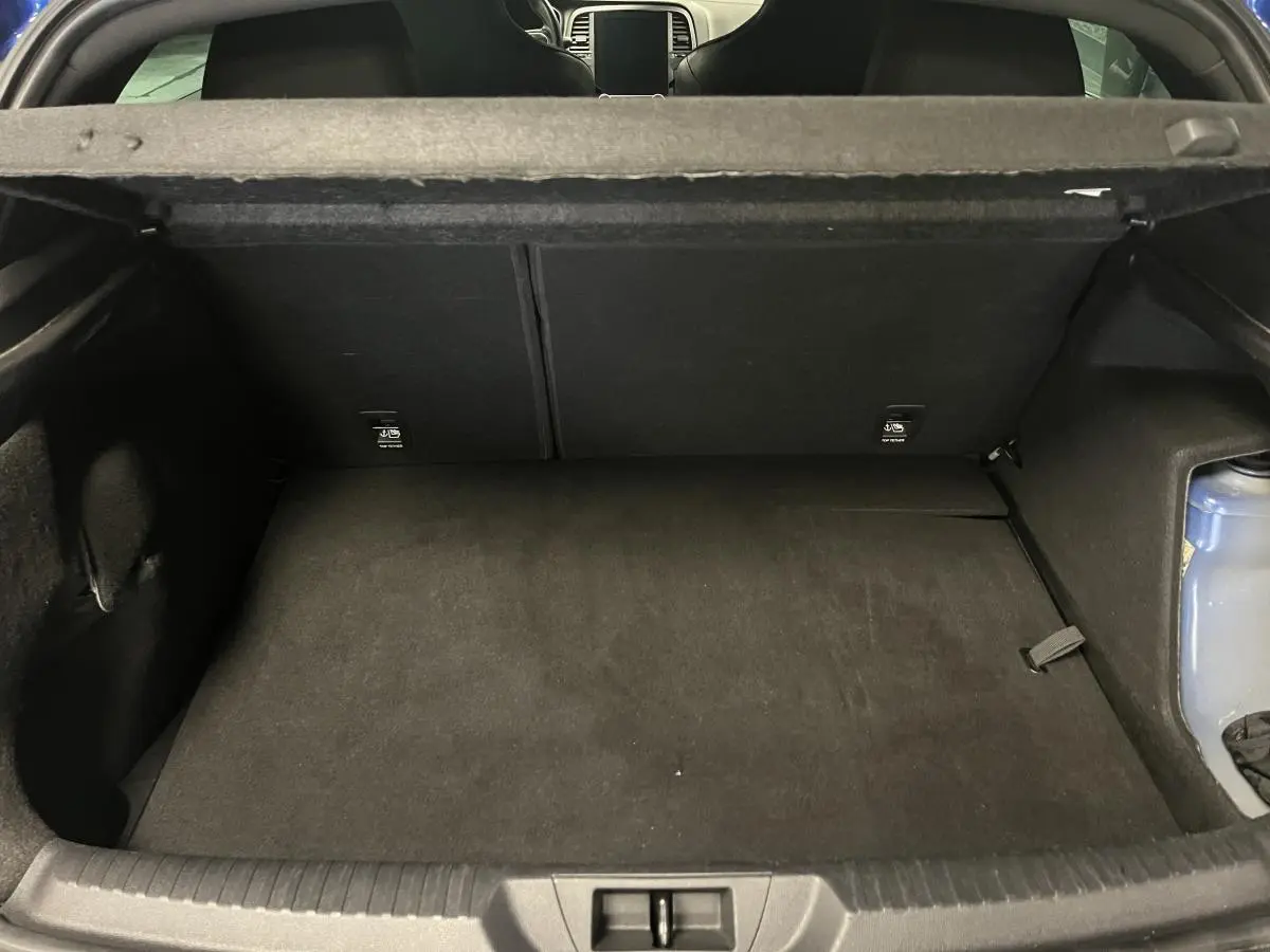Coffre ouvert de la Renault Mégane hybride rechargeable bleue, montrant un espace de rangement noir et la trappe arrière.