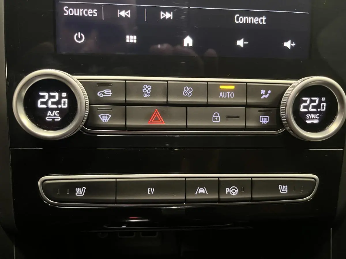 Gros plan sur la console centrale de la Renault Mégane hybride bleue, affichant la climatisation bi-zone et commandes EV.