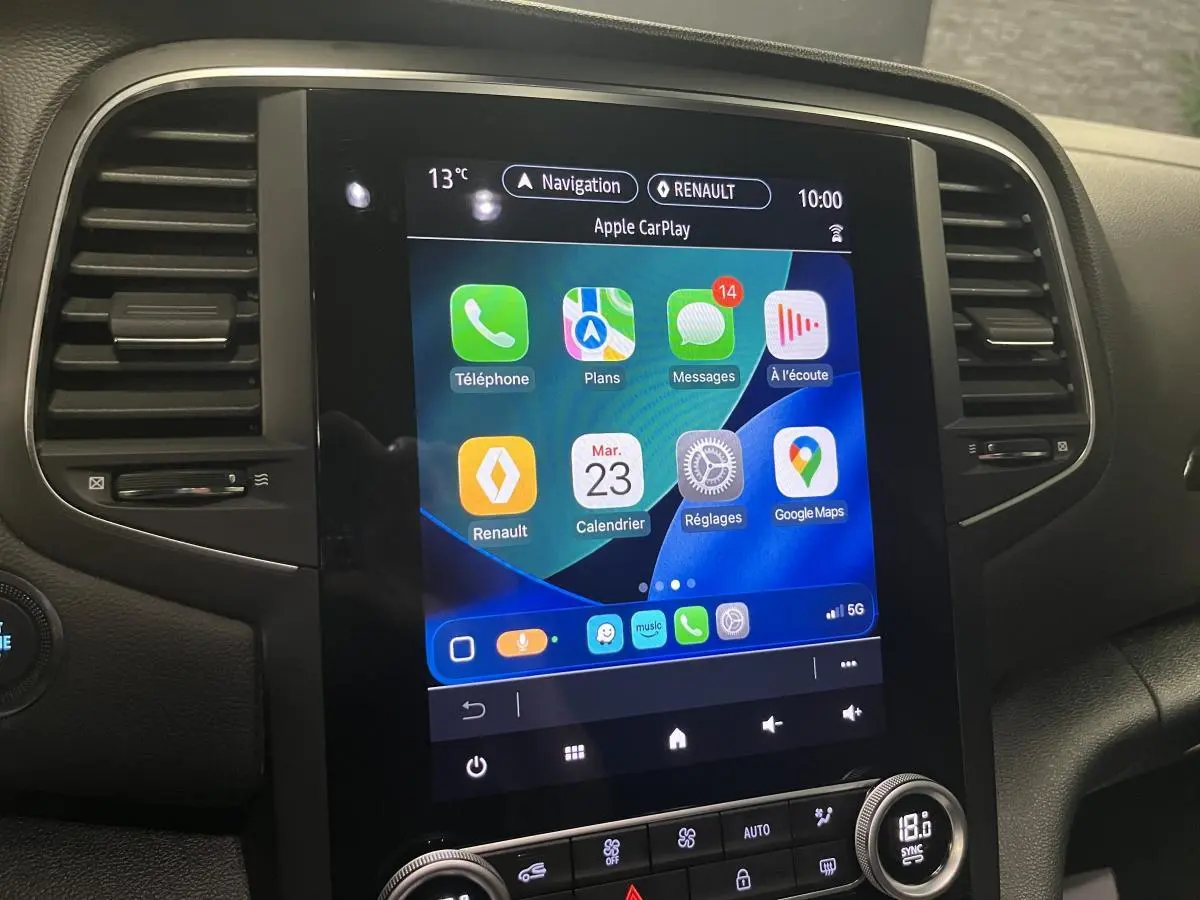 Écran tactile central du tableau de bord de la Renault Mégane hybride, affichant Apple CarPlay en intérieur noir.