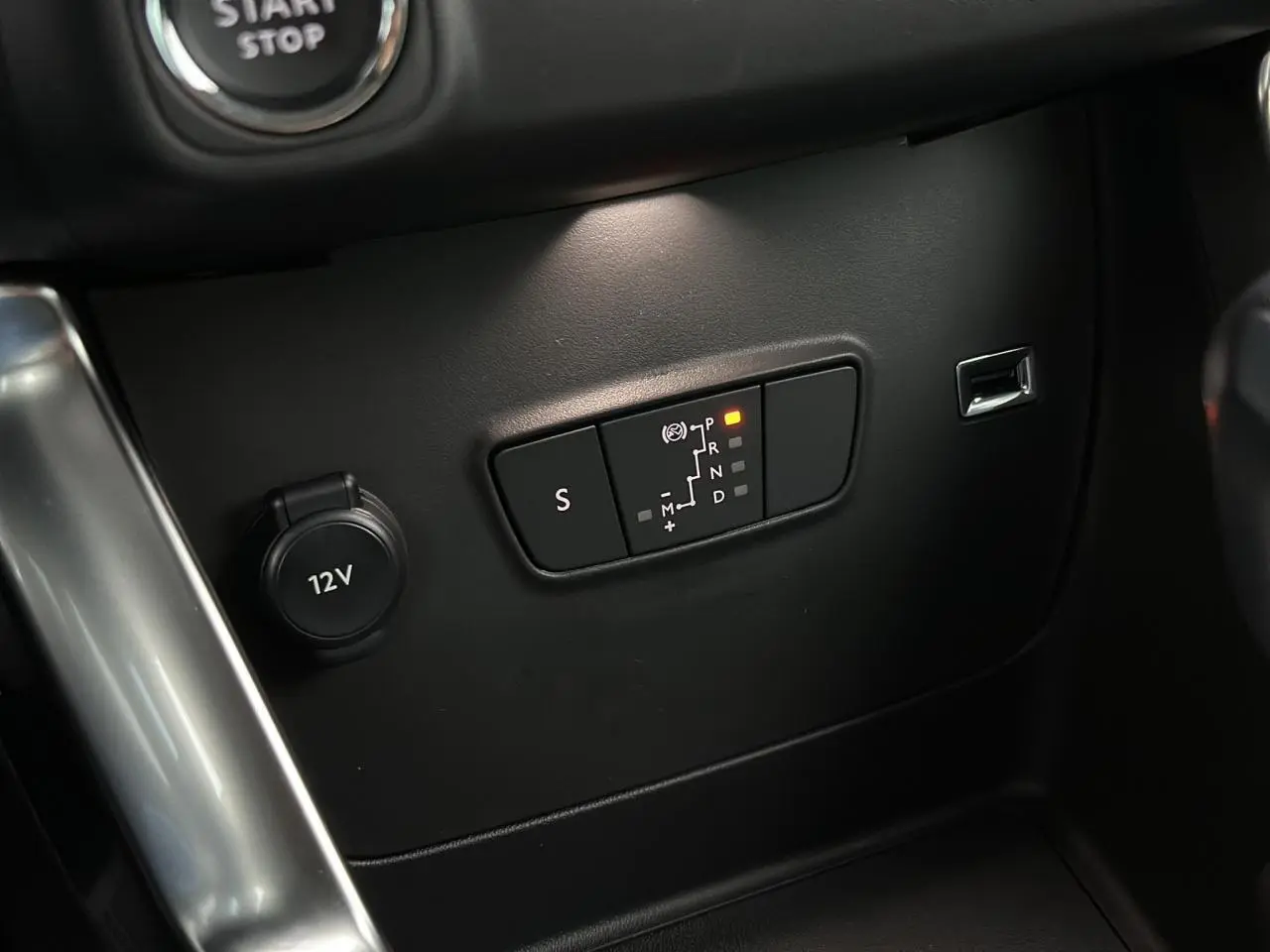 Gros plan sur la commande de boîte automatique et prise 12V dans l'habitacle noir du Citroën C3 Aircross 2024.