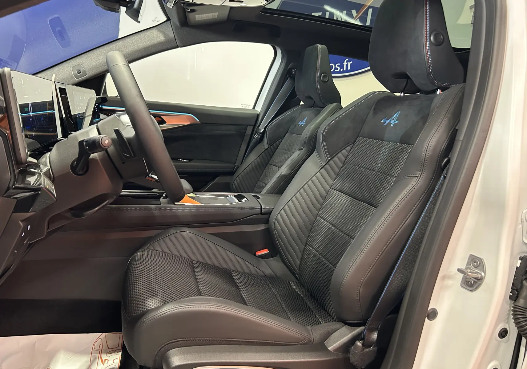 Vue intérieure côté gauche des sièges avant en cuir et alcantara noirs avec logo Alpine bleu sur Renault Austral blanc nacré.