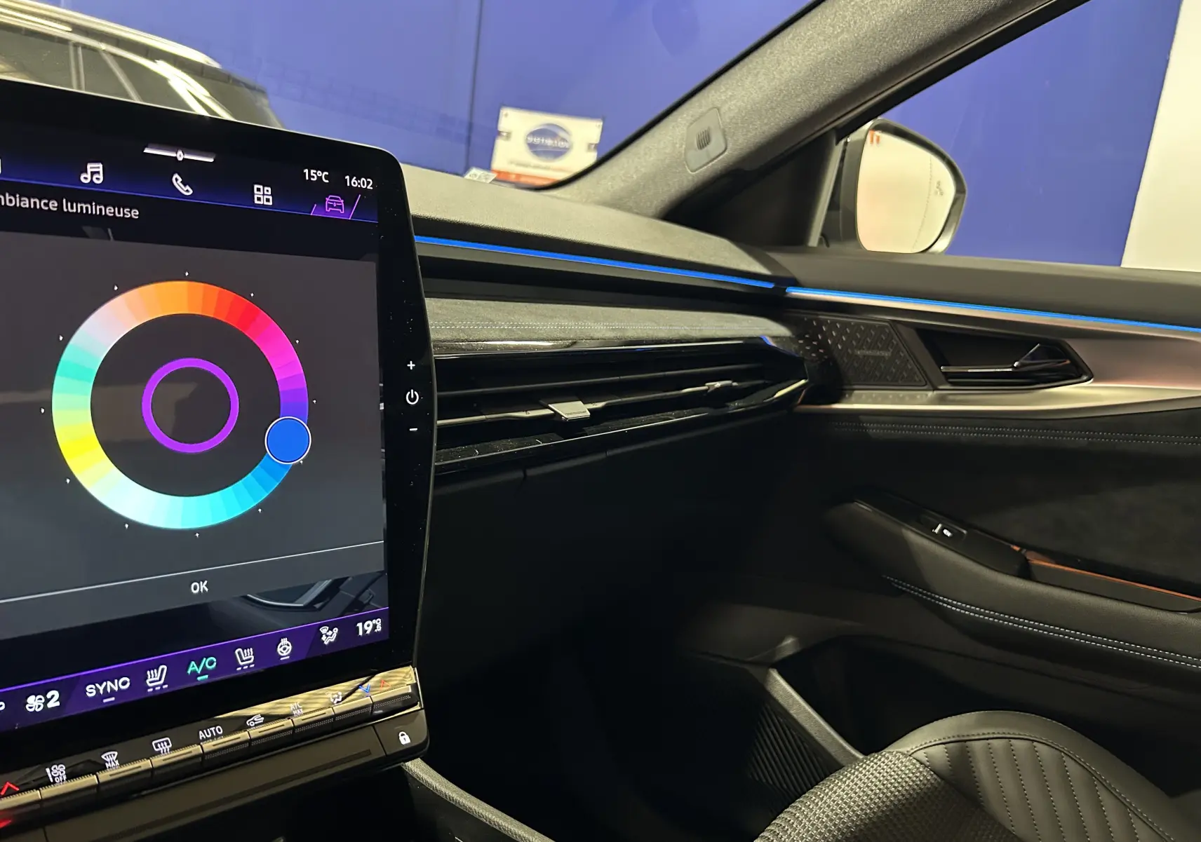 Vue intérieure côté passager du Renault Austral blanc nacré satin, avec écran tactile et éclairage d'ambiance bleu.