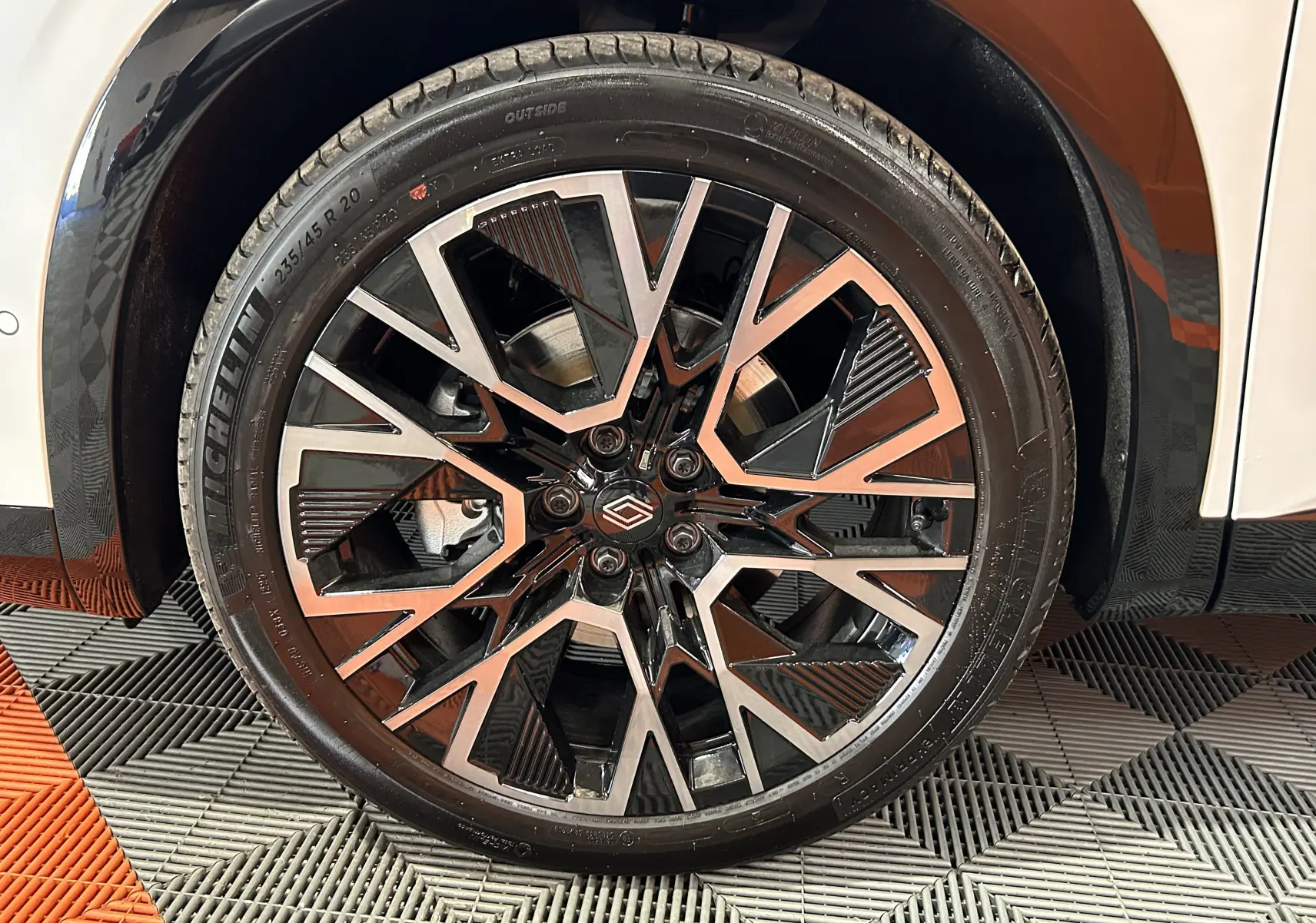 Gros plan sur la jante avant droite noire et argentée du Renault Austral blanc nacré satin, avec pneu Michelin visible.