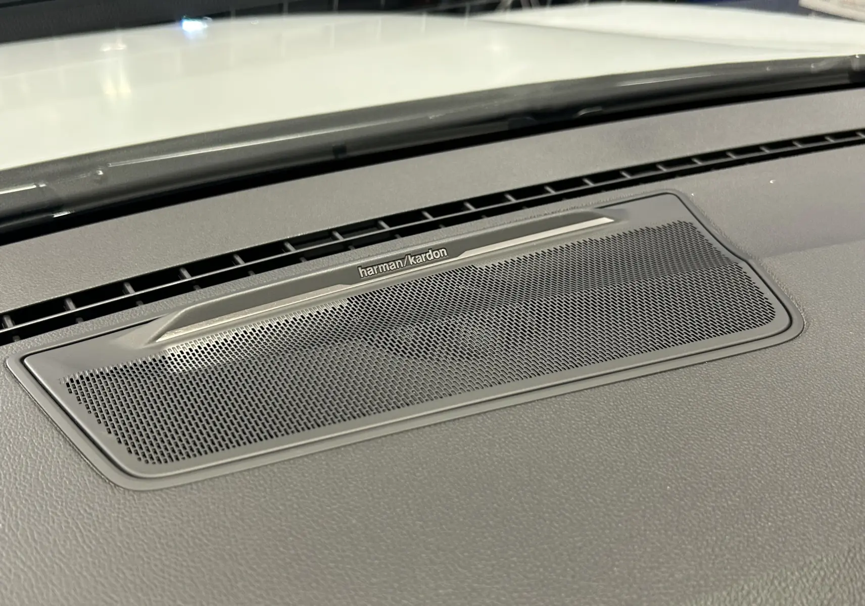 Gros plan sur la grille du haut-parleur Harman Kardon intégrée au tableau de bord du Renault Austral blanc nacré.