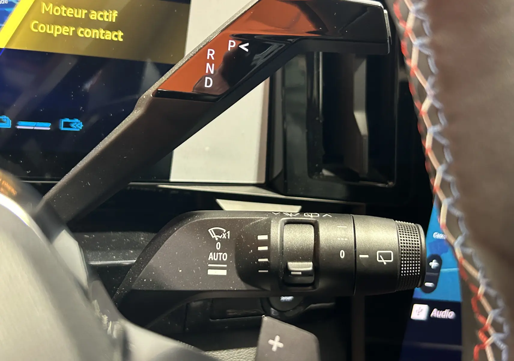 Gros plan sur la commande de feux et essuie-glaces du Renault Austral blanc nacré satin, avec affichage digital en arrière-plan.