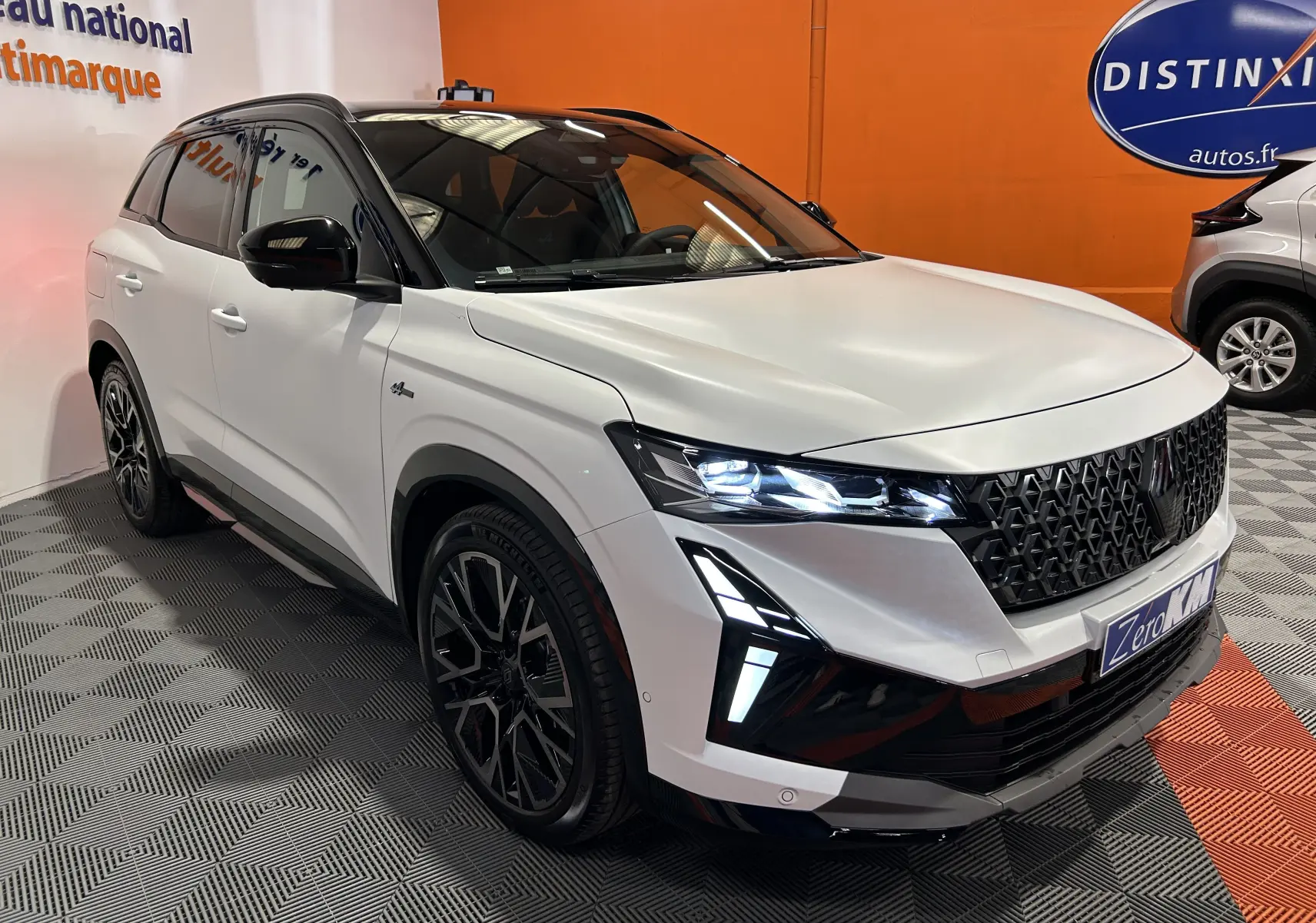 Renault Austral blanc nacré satin en 3/4 avant droit, avec calandre noire et phares LED allumés.