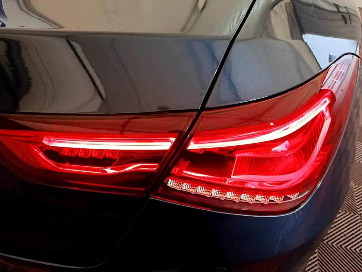 Gros plan sur le feu arrière droit rouge d'une Mercedes CLA 180 d Business Line blanche, détails lumineux nets.
