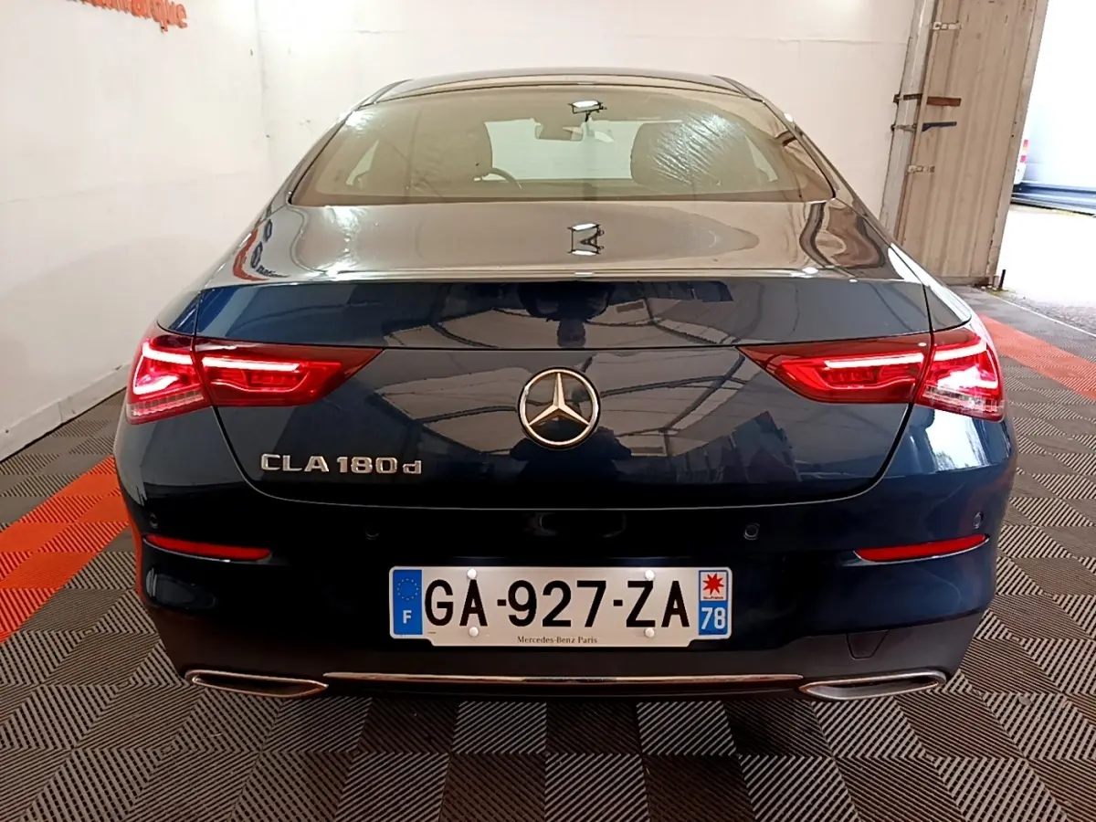 Vue arrière d'une Mercedes CLA 180 d noire avec feux LED allumés et double sortie d'échappement chromée.