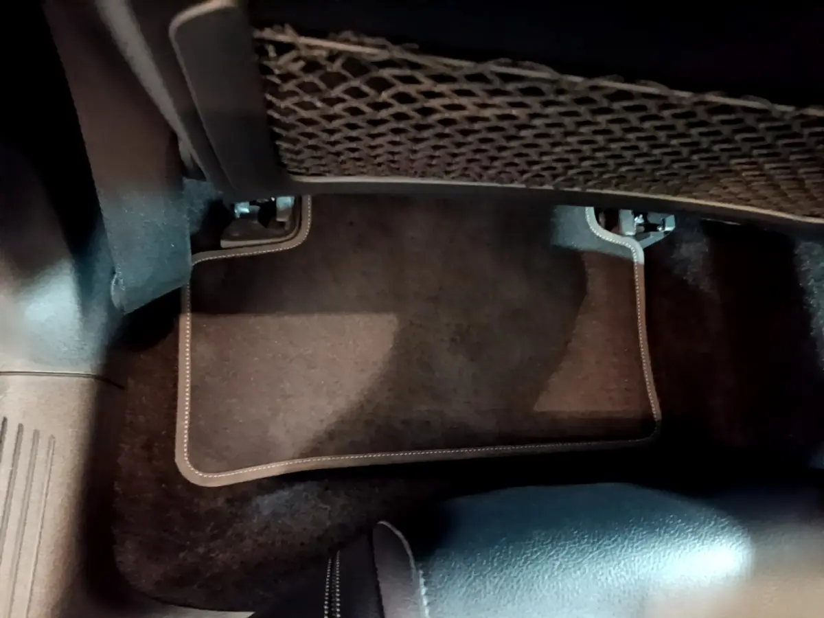 Vue intérieure du plancher côté passager arrière d'une Mercedes CLA 180 d Business Line blanche, tapis noir avec surpiqûres.