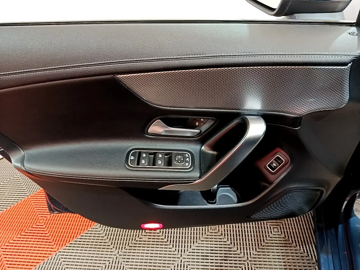 Vue intérieure côté gauche de la porte d’une Mercedes CLA 180 d Business Line 2021 avec commandes électriques et poignée alu.