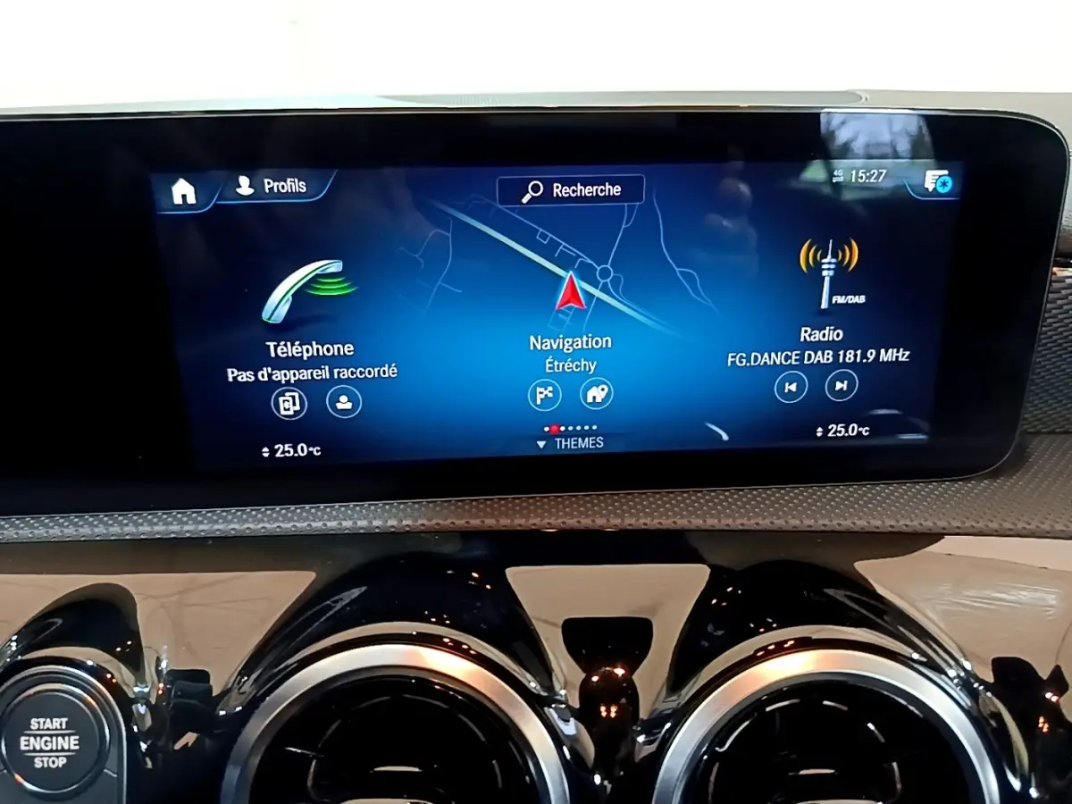 Vue rapprochée de l’écran tactile central et des aérateurs ronds chromés du tableau de bord de la Mercedes CLA 180 d blanche.