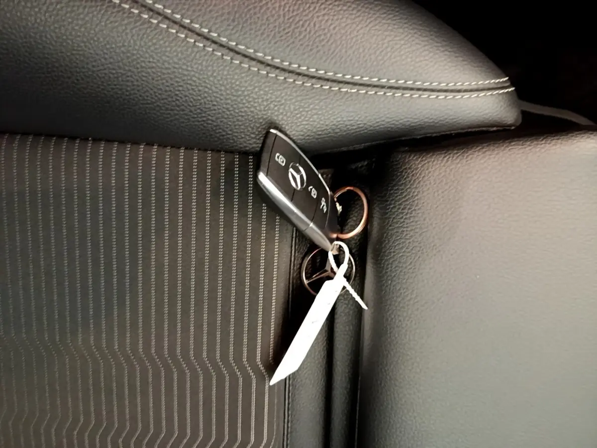 Gros plan sur la clé Mercedes posée sur un siège noir à coutures blanches, intérieur de la CLA 180 d Business Line.