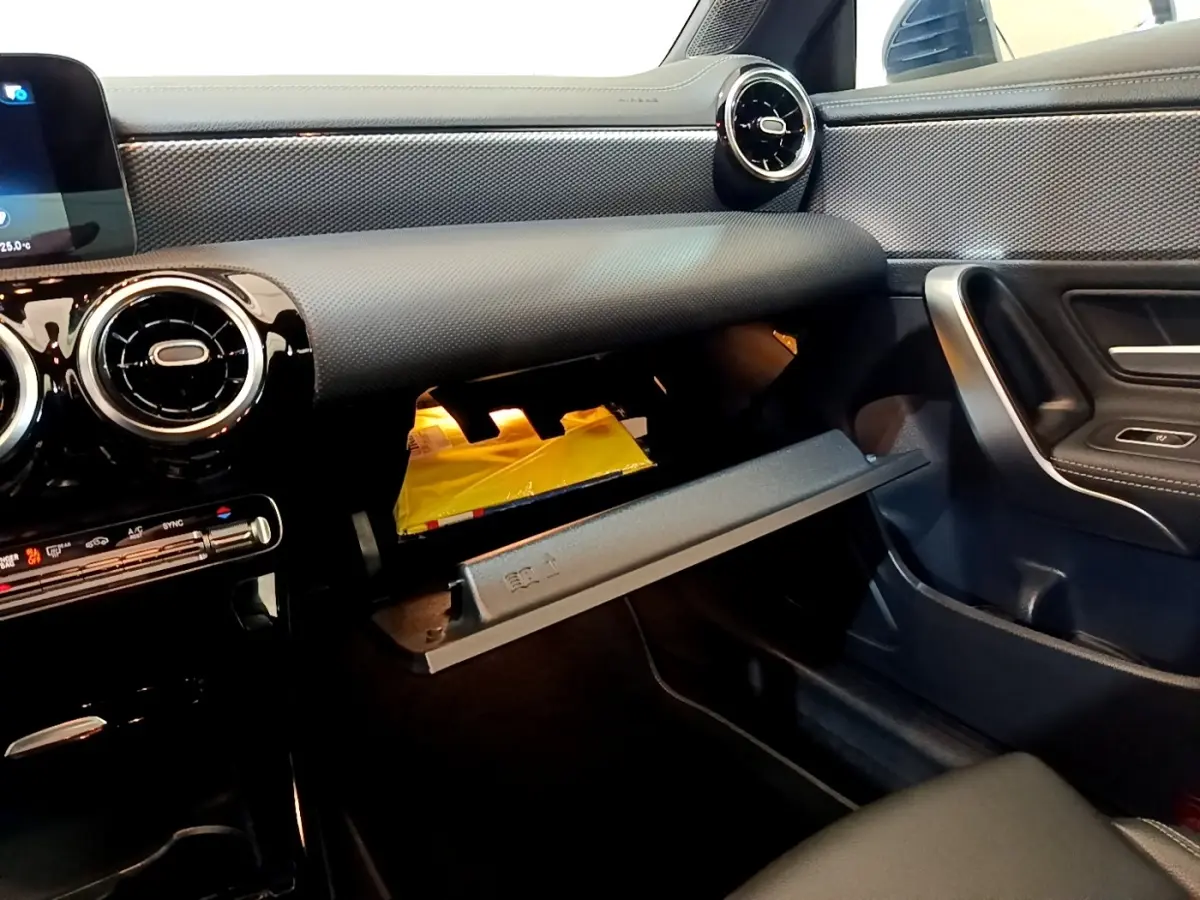 Vue intérieure côté passager de la Mercedes CLA 180 d Business Line 2021, tableau de bord noir et boîte à gants ouverte.