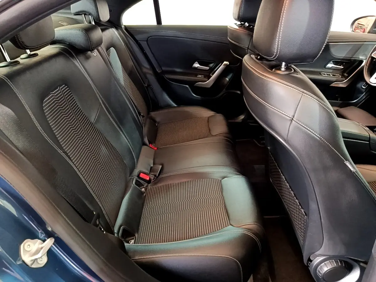 Vue intérieure arrière côté gauche sur les sièges noirs en cuir et tissu de la Mercedes CLA 180 d Business Line blanche.