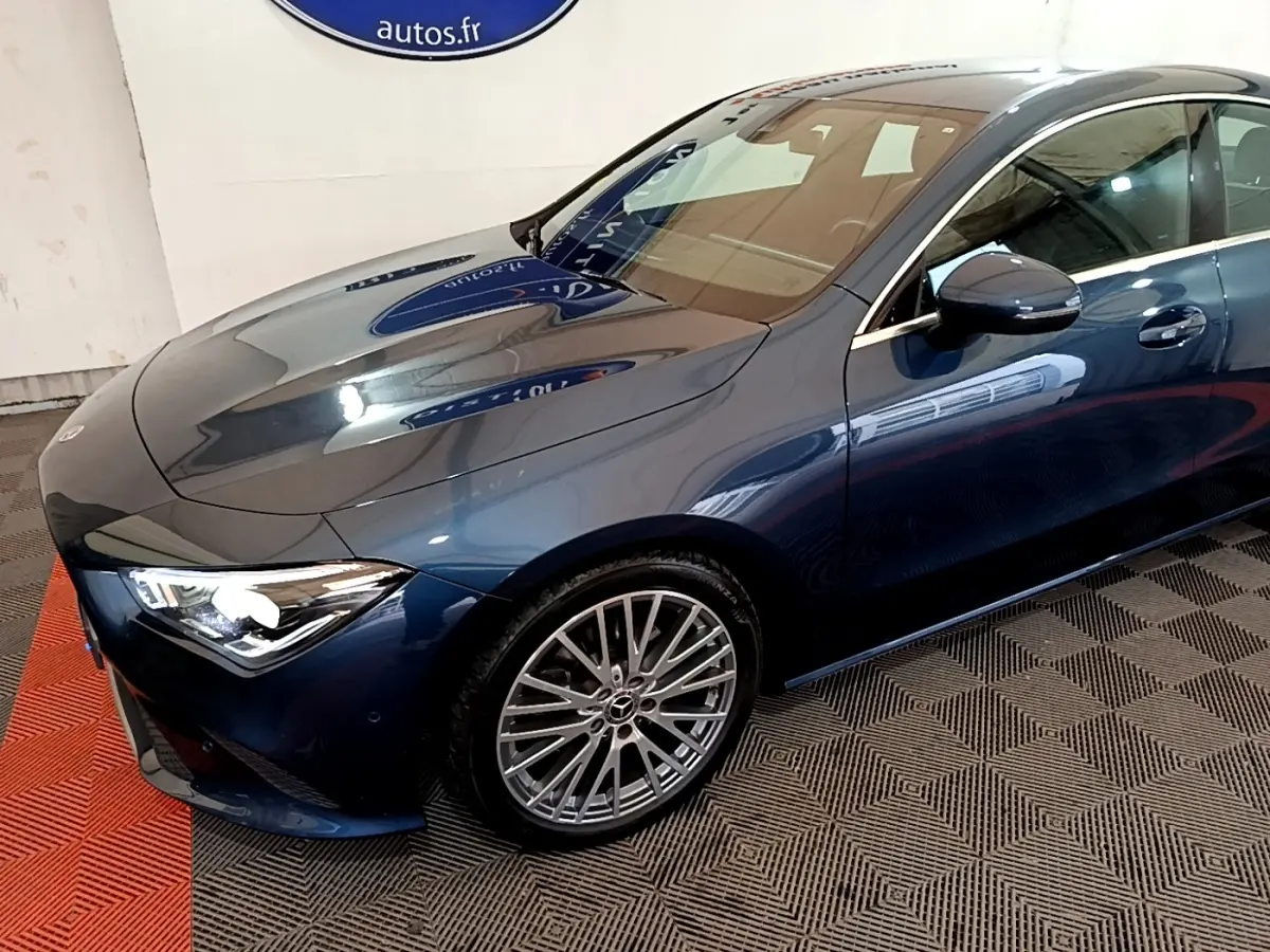 Vue 3/4 avant droit d'une Mercedes Classe CLA bleu métallisé avec jantes alliage multi-branches et phares LED allumés.