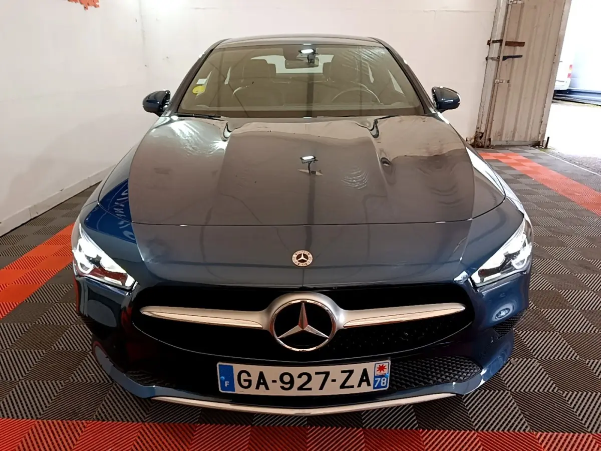Vue avant d'une Mercedes Classe CLA 180 d Business Line 2021 en bleu foncé avec calandre chromée et phares LED allumés.