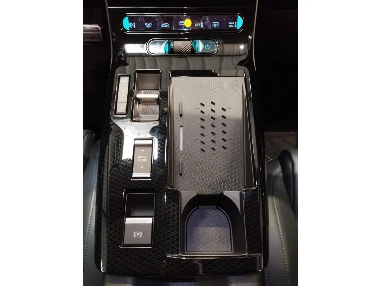 Vue plongeante sur la console centrale noire brillante du Citroën C5 Aircross avec commandes tactiles et rangement à induction.