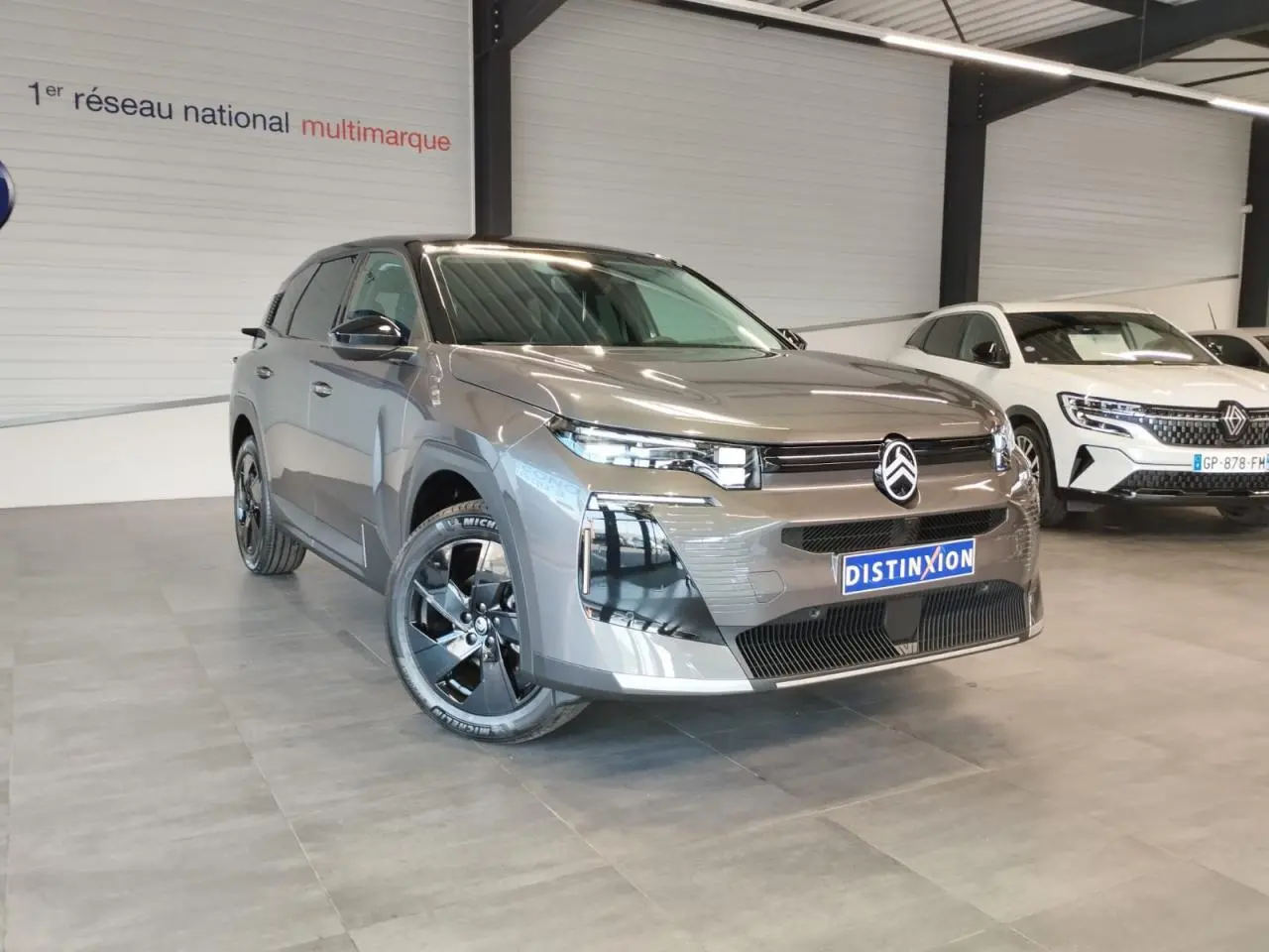 Vue 3/4 avant d'un Citroën C5 Aircross gris platine avec jantes alliage noires dans un showroom.