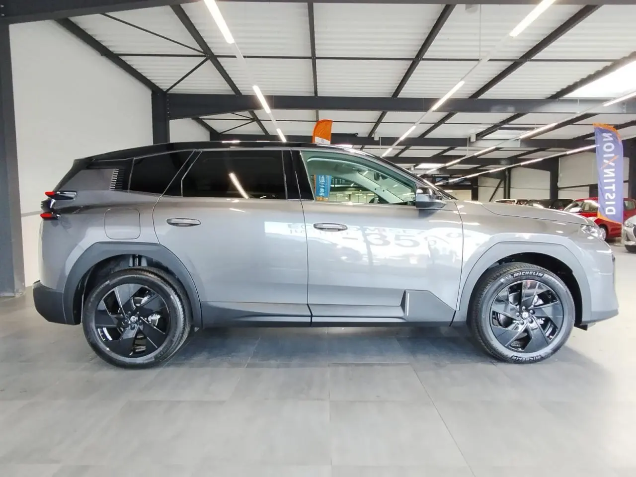 Vue latérale droite d'un Citroën C5 Aircross gris platine avec jantes alliage noires en intérieur showroom.
