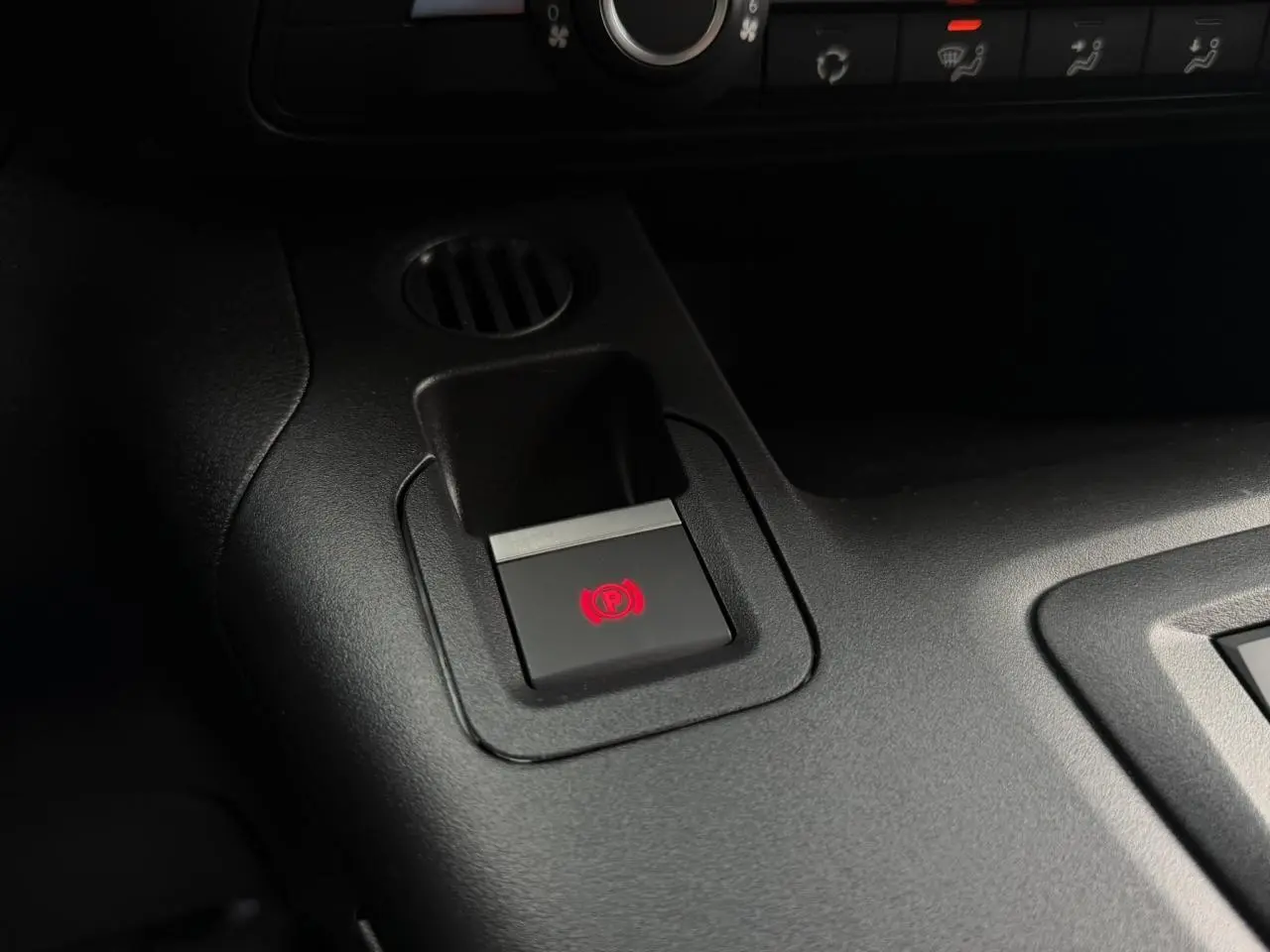 Gros plan sur le bouton de frein de stationnement électrique rouge dans l'habitacle noir du Citroën Berlingo Van XL 2026.