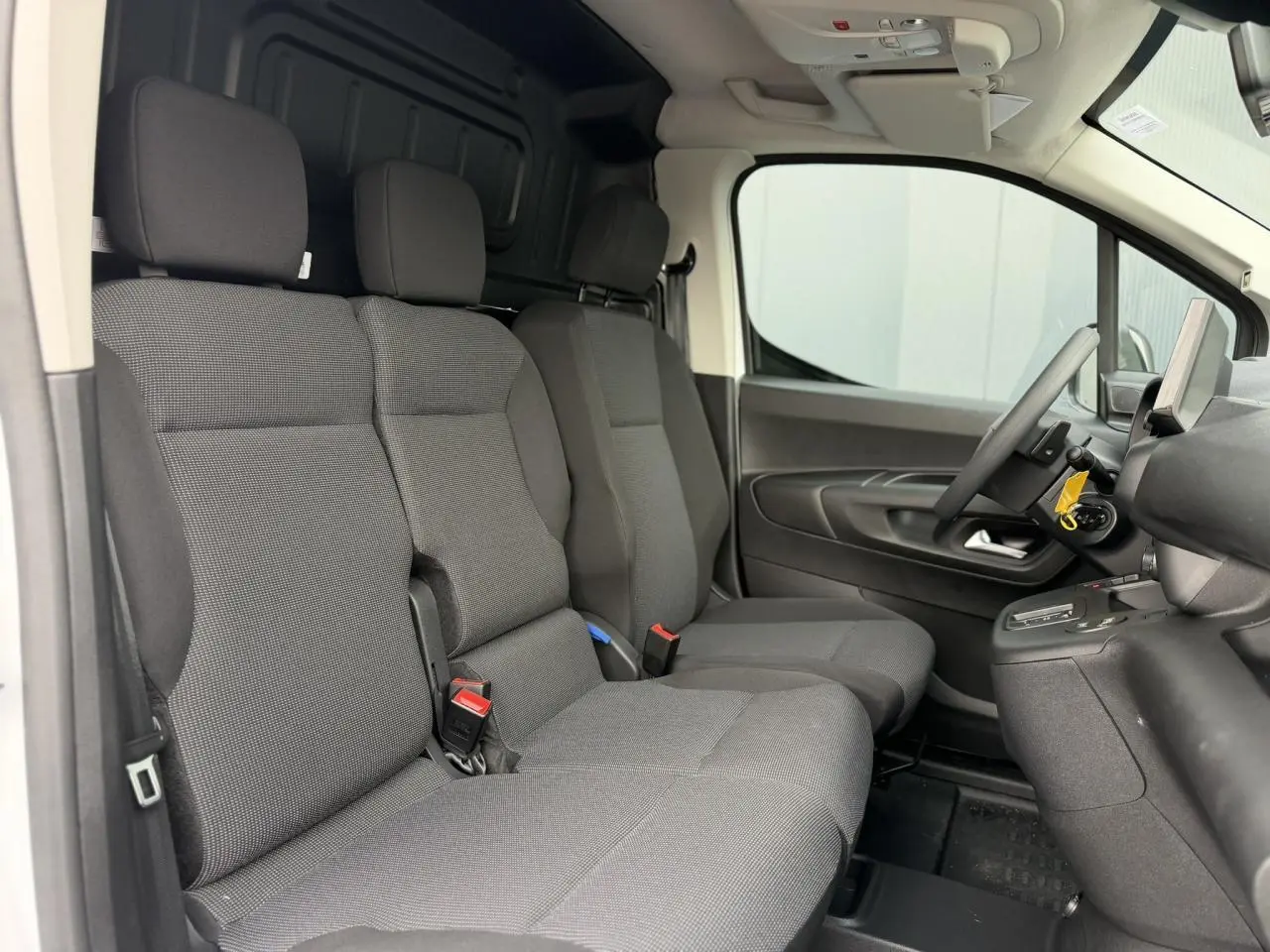 Vue intérieure côté conducteur du Citroën Berlingo Van XL 2026, sièges tissu gris et plancher bois visible derrière.