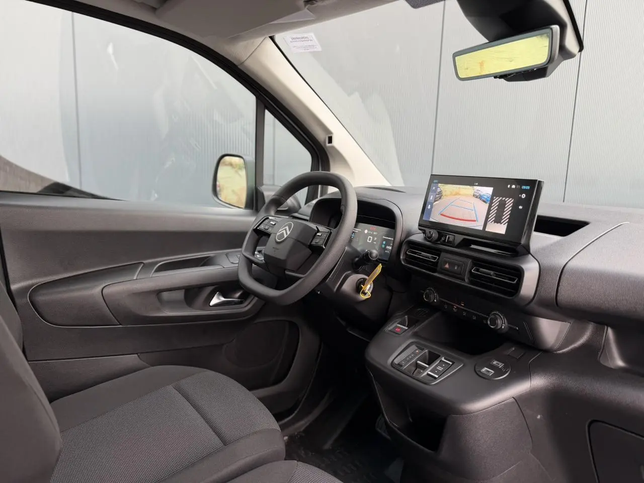 Vue intérieure côté conducteur du Citroën Berlingo blanc Icy, avec tableau de bord numérique et écran tactile de recul.