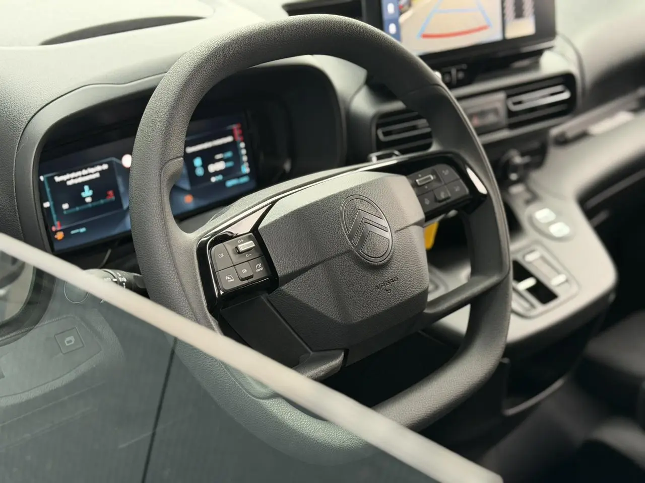 Vue rapprochée du volant multifonctions noir du Citroën Berlingo 2026 avec tableau de bord numérique et écran tactile.
