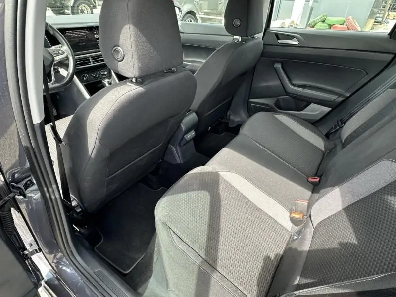 Vue intérieure arrière côté droit d'une Volkswagen Polo 2024 gris foncé, montrant les sièges arrière et l'avant du véhicule.