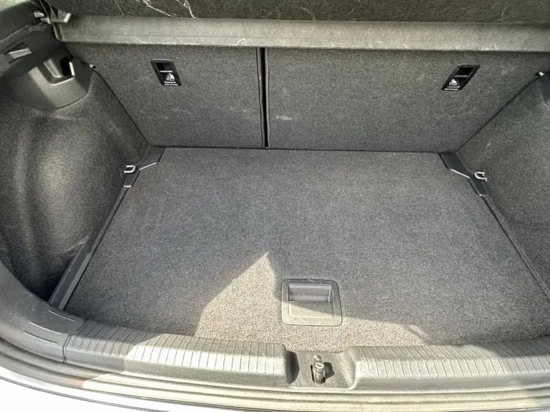 Coffre vide vu de dessus du Volkswagen Polo 1.0 TSI 95 DSG Life 2024 en gris foncé métal, tapis gris et fixations visibles.