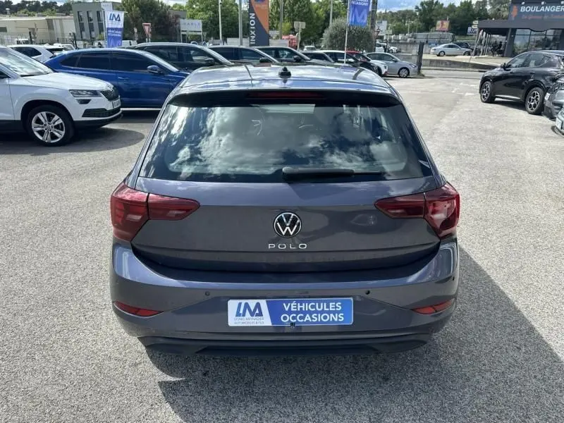 Vue arrière d'une Volkswagen Polo 2024 gris foncé métal avec logo et feux arrière distinctifs sur parking.