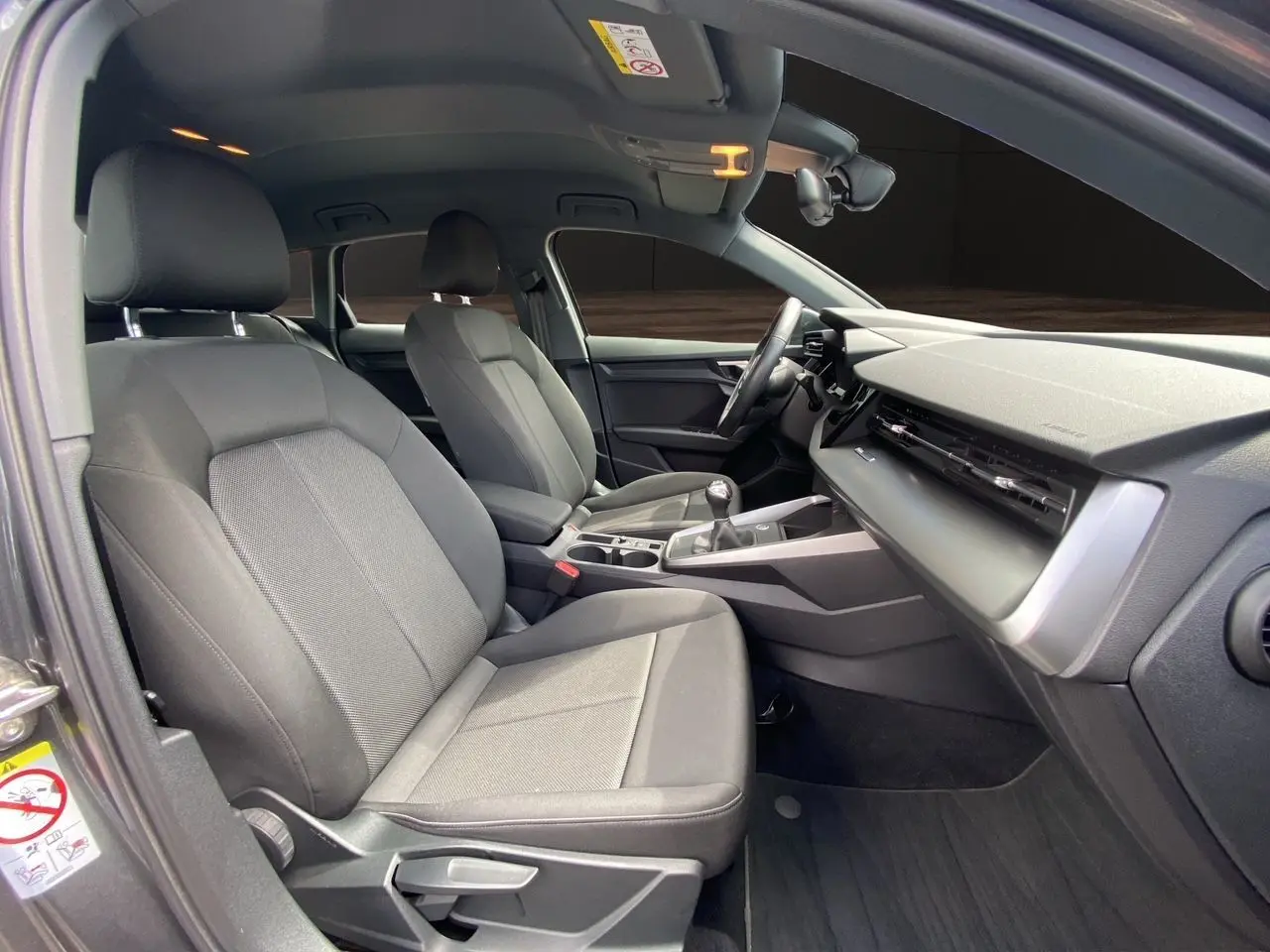 Vue intérieure côté conducteur de l'Audi A3 Sportback 30 TFSI 2021 avec sièges tissu noir et tableau de bord moderne.