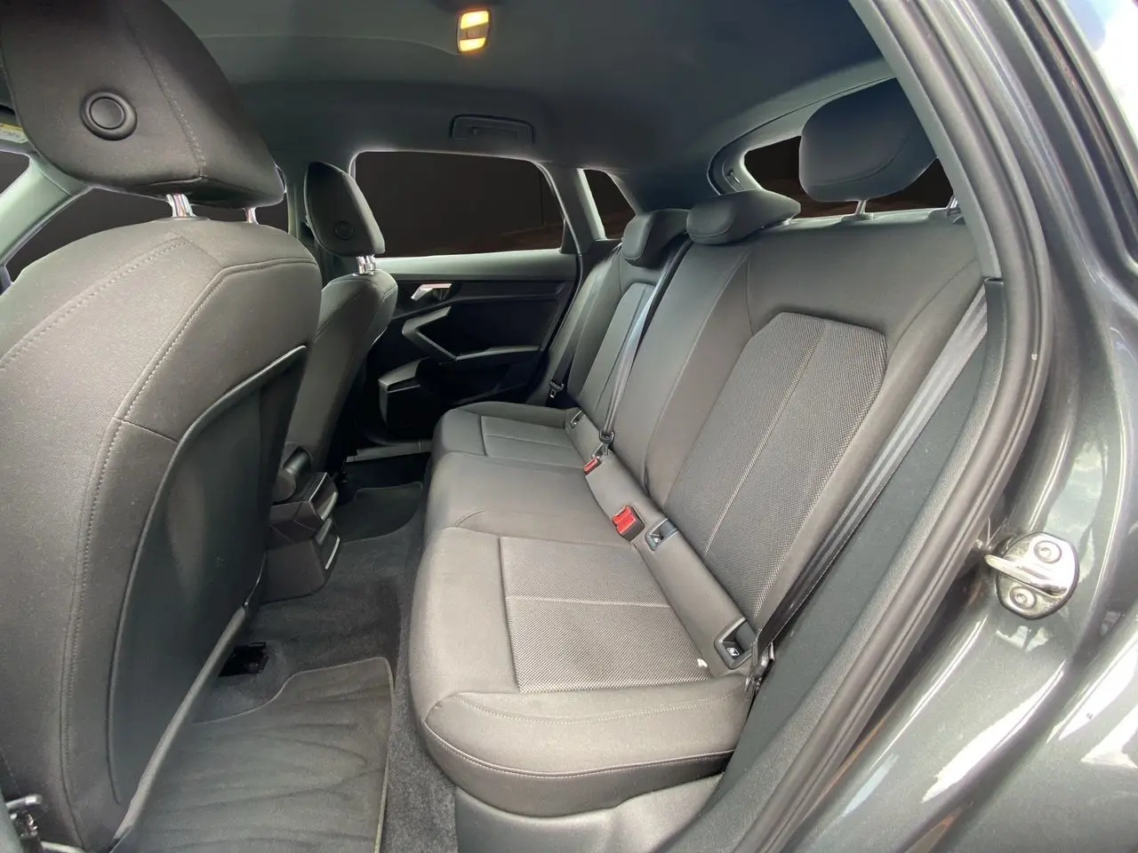 Vue intérieure arrière droite de l'Audi A3 Sportback 30 TFSI 110 S-Line 2021 avec sièges tissu noir et portières gris Daytona.